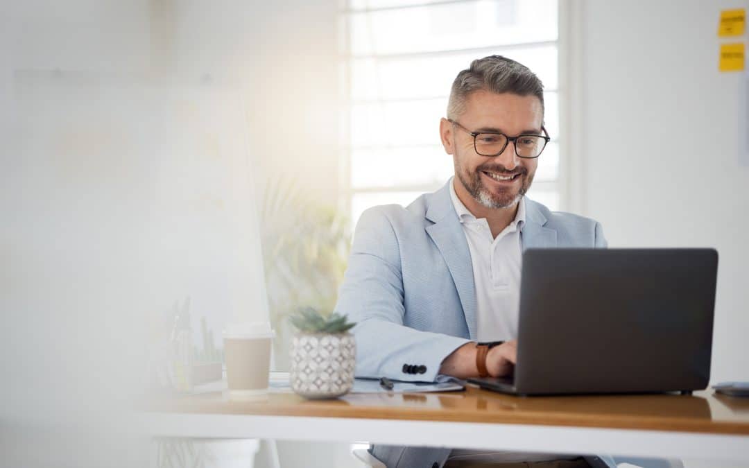 man smiling looking at computer - Chronos Body Health and Wellness